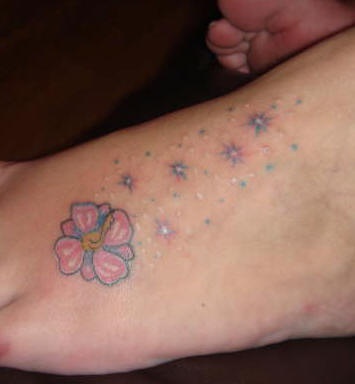 tatuaje en el pie de hibisco con estrellas brillando
