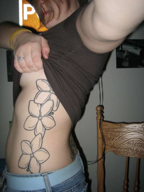 Le tatouage des silhouettes de fleurs d&quothibiscus sur le flanc