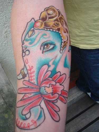 tatuaje de la cara de Ganesha con flores de color