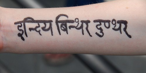 tatuaje en el brazo de escritos Sánscrito
