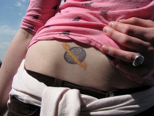 Colourful, turning interesting planet hip tattoo