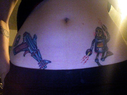 Tatuaje en la cadera, pistola y robot que baila