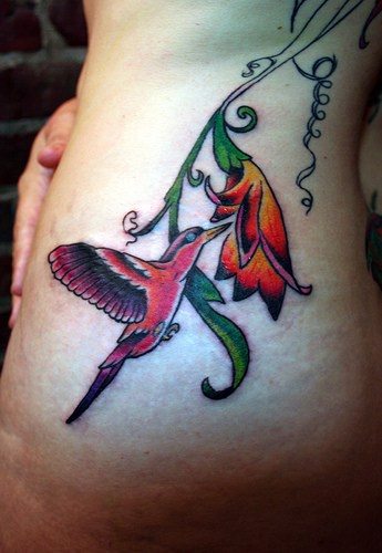 Tatuaje en la cadera, colibrí que recoge el néctar de una flor