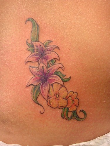 Tattoo von schäner Pflanze mit verschiedenen Blumen  an der Hüfte