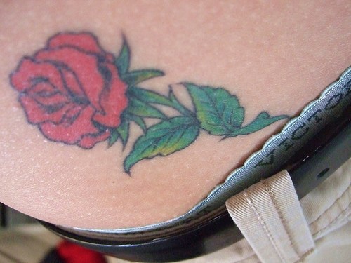 Tatuaje en la cadera, rosa realista con tallo y hojas