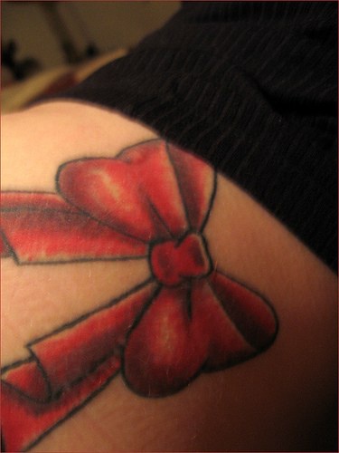 Un beau nœud rouge tatouage sur la hanche pittoresque