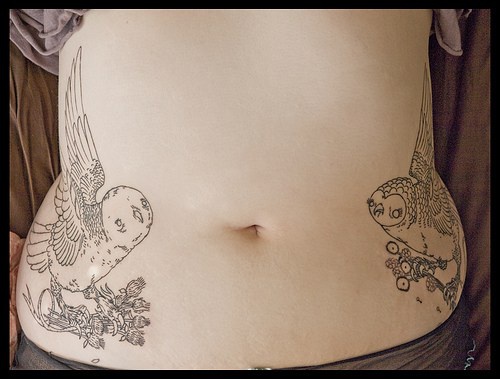 Two owls with risen wings hip tattoo
