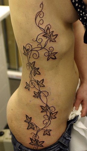 Very long plant, black, flowers, curls hip tattoo
