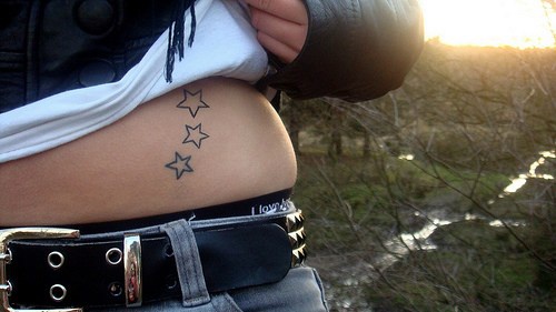 Tattoo von drei nichtfarbigen Sternen an der Hüfte