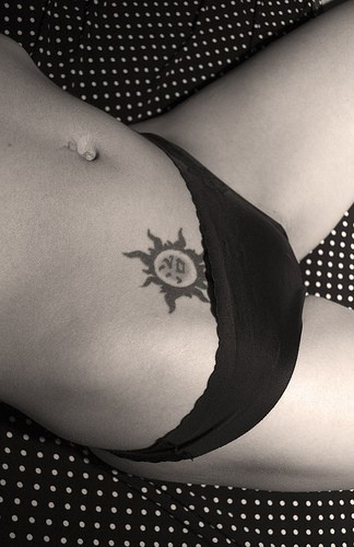 Black styled waving sun hip tattoo