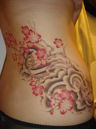 Tatuaje en la cadera, flores rojor en arbustos grises