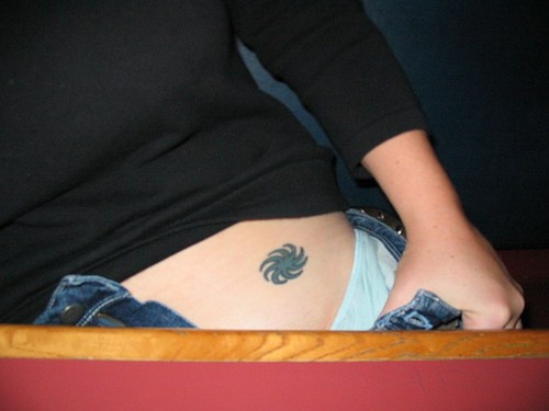 Tattoo von rundem kleinem Zeichen an der Hüfte