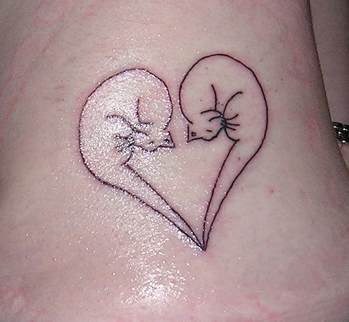 Tatuaje en la cadera, dos gatos que forman el corazón, descolorido