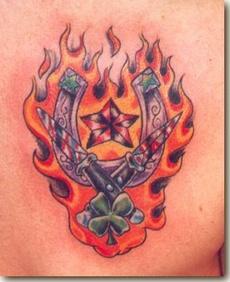 Tatuaje multicolor de una herradura en el fuego, dos cuchillos y una estrella