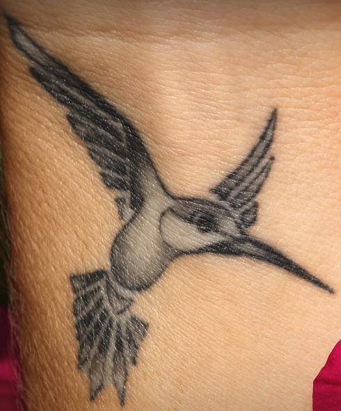 Tatuaje minimalista de un colibrí con alas abiertas.
