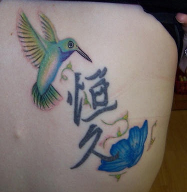 Tatuaje multicolor de un colibrí, unos jeroglíficos chinos y una flor azul