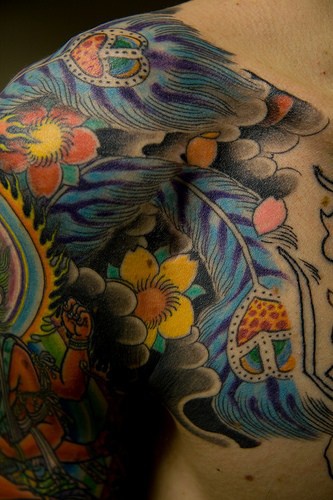Tatuaje estilo asiatico de plumas azules y flores