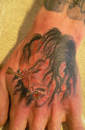 Tatuaje en la mano de un samurai japonés con la flecha en el ojo
