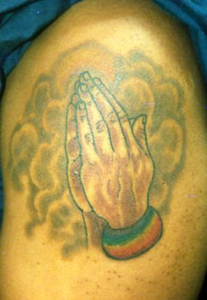 el tatuaje de las manos orantes en el humo hecho en color