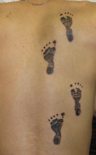 Baby footsteps tattoo on back