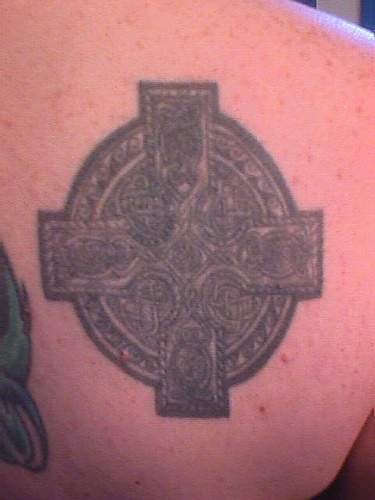 Tatuaje negro de una cruz en clavícula
