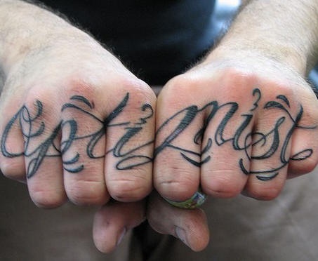Le mot optimiste tatouage sur les phalanges inscription en italique