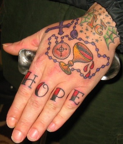Tatuaje en los nudillos, inscripción esperanza, cruz, cadena, copa con vino