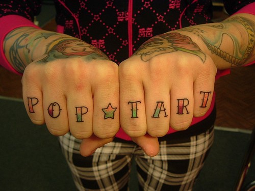 La scritta &quotpop tart " tatuata sulle dita