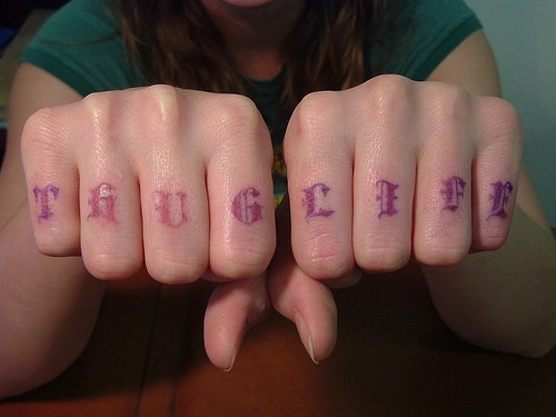 Tattoo mit stilisierter Inschrift &quotThug life&quotan Fingerknöcheln