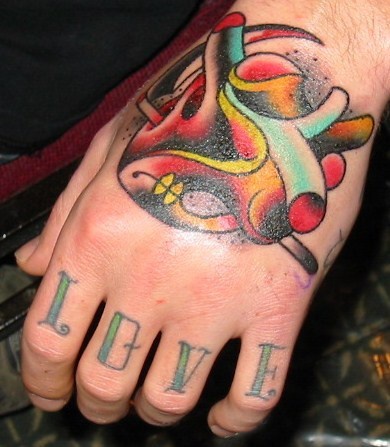 Le coeur tatouage sur la main et le mot l'amour sur les phalanges