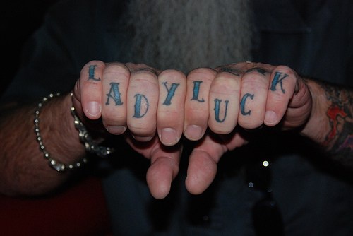 Tattoo mit stilisierter Inschrift &quotLady luck" in Blau an Fingerknöcheln