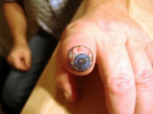 Tatouage d’un petit œil bleu au bout de doigt