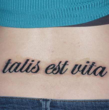 Le tatouage d&quotinscription Talis est vita sur le bas du dos