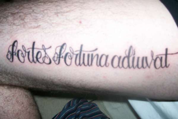 Tatuaje en pierna de una frase en latín