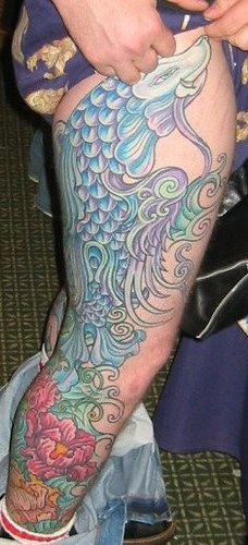 Tatuaggio colorato sulla gamba mostruoso pesce-gatto irreale con i fiori