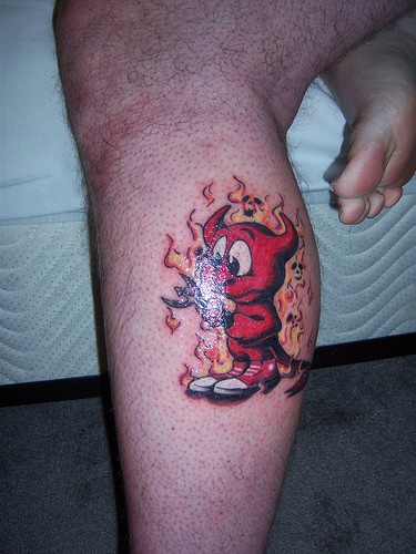 Tatuaje en la pierna, pequeño diablo rojo en el fuego
