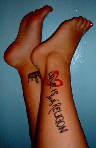 La scritta &quotLOVE IS MY RELIGON" con il cuore tatuata sulla gamba