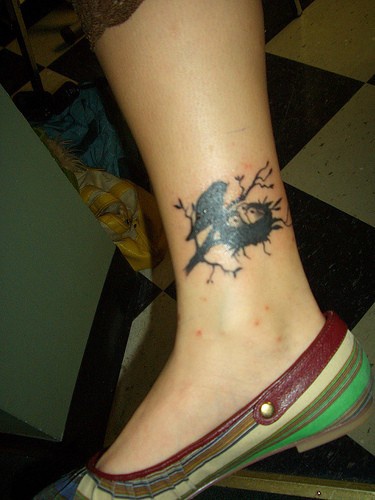 Leg tattoo, black bird with little birds in the nest