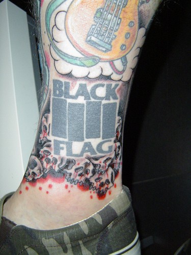 Curioso tatuaggio sulla gamba &quotBLACK FLAG" e la chitarra