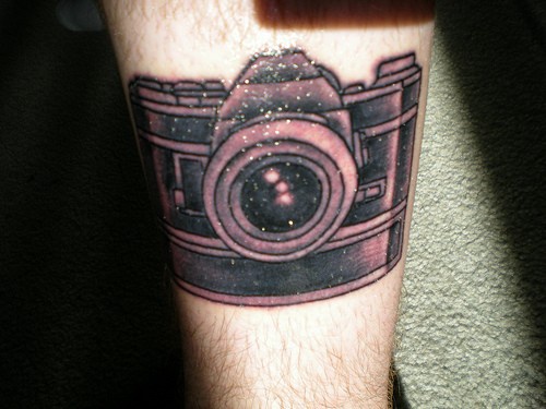 Grande camera fotografica tatuata sulla gamba