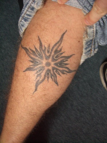 Bein Tattoo, brennender schwarzer Stern, kleiner Kreis