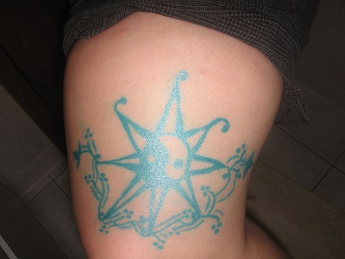 Tatuaggio azzurro sulla gamba il sole tribale