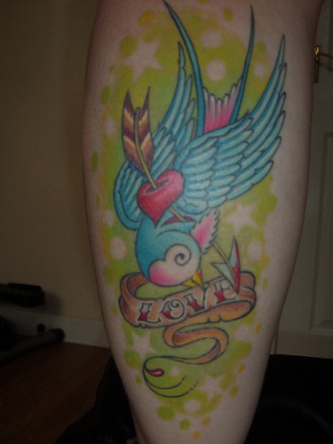 Tatuaje en la pierna, ave azul, saeta, inscripción