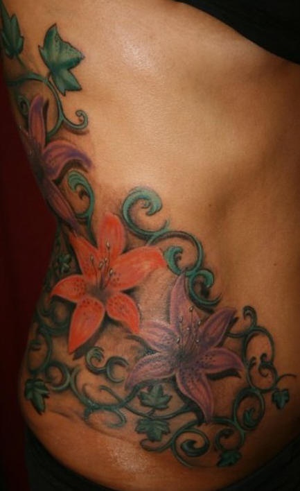 Un gros tatouage de fleurs de lys avec un lierre sur le flanc