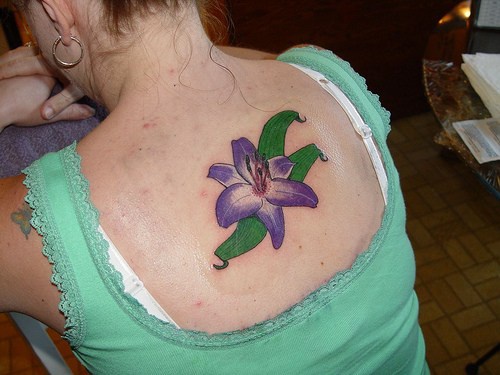 Tatuaje en espalda de lirio color violeta