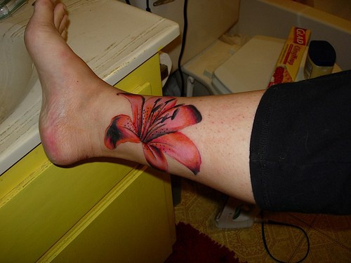 fiore rosso femminile sulla gamba tatuaggio