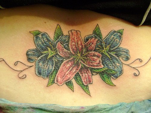 El tatuaje de unas flores de lirio color azul y rosa