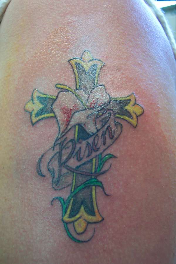 El tatuaje de una cruz y una flor de cala blanca