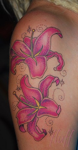 El tatuaje de dos Lirios de color rosa rodeados de muchos puntitos  y unas estrellas
