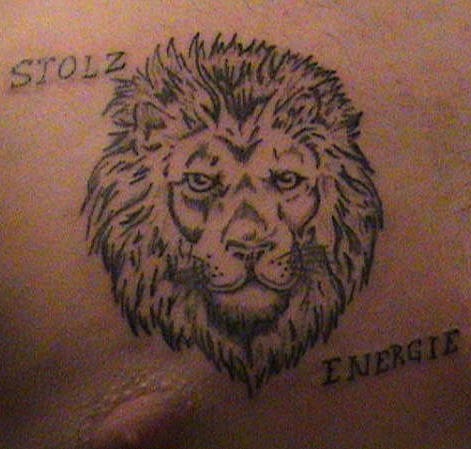 El tatuaje de la cabeza de un leon negro palabras en el pecho